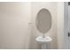 Elegant powder room with a pedestal sink, oval mirror, and neutral walls, creating a minimalist design at 521 Fife Ct, Gibsonville, NC 27249