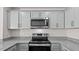 Stylish kitchen with stainless steel appliances, gray cabinets, and granite countertops at 523 Fife Ct, Gibsonville, NC 27249