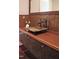 Close-up of a powder room featuring a glass vessel sink, wood countertop, and bronze faucet at 805 Greenwood Rd, Chapel Hill, NC 27514