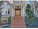 A beautiful exterior shot of a gray two-story house with a brick staircase leading to the elegant wood front door at 805 Greenwood Rd, Chapel Hill, NC 27514