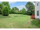 Lush green backyard with manicured lawn, mature trees, and access to the back deck at 1106 Bellenden Dr, Durham, NC 27713