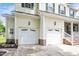 Spacious two-car garage with white doors, exterior lighting, and brick base in a bright home at 1106 Bellenden Dr, Durham, NC 27713