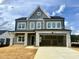 New two-story home with gray siding, stone accents, two-car garage, and an unfinished yard at 130 W Crescent Mills Blvd # Homesite 251, Wilson's Mills, NC 27520