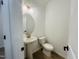 Stylish powder room featuring a pedestal sink, round mirror, toilet, and elegant lighting fixtures at 130 W Crescent Mills Blvd # Homesite 251, Wilson's Mills, NC 27520