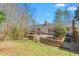 Backyard view of the house featuring a patio, deck, and a spacious lawn with mature trees at 1405 N Sellars Mill Rd, Burlington, NC 27217
