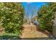Backyard brick pathway leading to a wooden ramp, surrounded by lush greenery and flowering bushes at 1405 N Sellars Mill Rd, Burlington, NC 27217