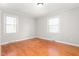 A bedroom with original hardwood flooring, base molding and two bright windows at 1405 N Sellars Mill Rd, Burlington, NC 27217