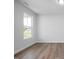 Modern bedroom with neutral walls, wood-look flooring, a large window with natural light, and white trim at 173 Wild Turkey Way, Lillington, NC 27546
