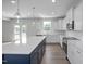 Modern kitchen with white cabinets, island with blue cabinets, quartz countertops, and stainless steel appliances at 173 Wild Turkey Way, Lillington, NC 27546