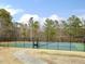 Community tennis court with a dark fence and surrounded by mature trees at 1961 Indianwood Ct, Raleigh, NC 27604