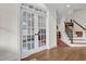 Hallway featuring hardwood floors, staircase, and elegant glass paneled doors at 204 Dartmoor Ln, Raleigh, NC 27614