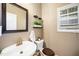 Compact powder room with a pedestal sink, dark wood toilet seat, and decorative shelving at 3659 Coach Lantern Ave, Wake Forest, NC 27587