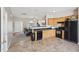 Open-concept kitchen featuring wood cabinets and black appliances, with a view into the living area at 3809 Volkswalk Pl, Raleigh, NC 27610