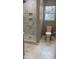 Updated bathroom featuring a glassed-in shower, marble-look tile, new toilet, and a window at 471 Merriman St, Henderson, NC 27536