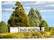 Community sign surrounded by lush landscaping featuring mature trees and colorful flower beds at 5818 Humanity Ln, Raleigh, NC 27616
