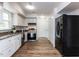 Galley kitchen with white cabinets, stainless steel appliances, and wood flooring, next to black refrigerator at 7408 Stable End Rd, Raleigh, NC 27613