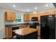 Well-lit kitchen with wooden cabinets, black appliances, and center island at 765 Townsville Landing Rd, Henderson, NC 27537