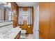 Cozy bathroom featuring wood paneled walls, a shower/tub combo, and natural light from the window at 902 Bragg St, Sanford, NC 27330