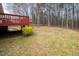 Spacious backyard with mature trees, flowering bushes, and a red painted deck at 936 Amersham Ln, Wake Forest, NC 27587