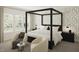 A serene main bedroom showcasing a four-poster bed, soft wallpaper, and cozy armchairs at 108 N Stonemill Trl # Homesite 254, Wilson's Mills, NC 27520