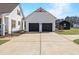 A two car garage boasts black doors and a concrete driveway, providing ample parking space at 118 Riverwood Dr, Fuquay Varina, NC 27526