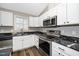 A kitchen with stainless steel oven, microwave, granite countertops, and white cabinetry at 120 W College St, Oxford, NC 27565