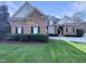 Charming brick home featuring black shutters, arched windows, a well-manicured lawn, and a circular driveway at 138 Parkdale Ln, Clayton, NC 27520