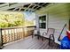 View of covered porch with wooden floors, chairs, and wooded views beyond the railing at 201 Colonial Ave, Goldston, NC 27252