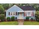 Charming blue home featuring red shutters, a brick foundation, and a well-maintained front yard at 214 Grace St, Oxford, NC 27565