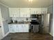 Featuring stainless steel appliances, the cozy kitchen has white cabinets and light countertops at 214 Grace St, Oxford, NC 27565