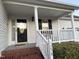 Charming front porch with black front door, white railing, columns, and manicured landscaping at 254 Pedernales Dr, Smithfield, NC 27577