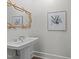 Charming bathroom features a pedestal sink, unique bamboo-style mirror, and stylish artwork at 2710 Cambridge Rd, Raleigh, NC 27608
