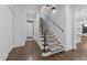 Elegant staircase featuring patterned carpet, a black iron handrail, and modern sconce lighting at 2710 Cambridge Rd, Raleigh, NC 27608