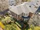Aerial view of a brick home with a shingled roof, surrounded by a meticulously landscaped garden and mature trees at 2820 Glenwood Gardens Ln # 101, Raleigh, NC 27608
