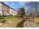View of a multi-story residential building with balconies and a creek running through the landscaped backyard at 2820 Glenwood Gardens Ln # 101, Raleigh, NC 27608