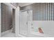 A white tiled bathroom with a glass enclosed shower, jacuzzi tub, and checkered wall paper at 2820 Glenwood Gardens Ln # 101, Raleigh, NC 27608
