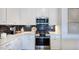 Well-equipped kitchen boasts white countertops, stainless steel appliances, and a decorative black tiled backsplash at 284 Hank Way, Angier, NC 27501