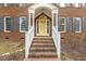 Close up of the brick front exterior with white railing, brick steps and charming yellow front door at 3715 Rawls Church Rd, Fuquay Varina, NC 27526