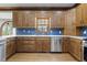 Kitchen featuring wood cabinets, stainless appliances, blue tile backsplash, and hardwood floors at 3715 Rawls Church Rd, Fuquay Varina, NC 27526