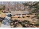 An aerial view of a brick single-story home with a gravel driveway and mature trees at 4508 Regis Ave, Durham, NC 27705