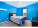 A bright blue bedroom with a patterned bedspread, a ceiling fan, and a window at 5315 Glenmorgan Ln, Raleigh, NC 27616
