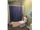 A small bathroom with a toilet, a rug on the floor, and a shower with a dark blue curtain at 614 Oak St, Burlington, NC 27215