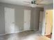 A bedroom with neutral walls and carpet flooring showcasing three doors and a ceiling fan at 6225 Tributary Dr, Raleigh, NC 27609