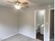 A bedroom showcasing a ceiling fan, neutral walls and carpet, adjoins an ensuite bathroom at 6225 Tributary Dr, Raleigh, NC 27609