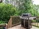 This back deck offers a stainless grill and a view of a wooded lot at 730 Toms Creek Rd, Cary, NC 27519
