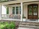 Inviting front porch with stone accents, elegant front door and a cozy seating area at 730 Toms Creek Rd, Cary, NC 27519