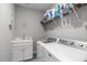 Well-organized laundry room with white cabinets, sink, washer, dryer, and storage shelf at 74 Powderhorn Pt, Garner, NC 27529