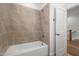 Bathroom featuring a bathtub with light brown tile walls, and a white door at 112 Pointe Park Cir, Holly Springs, NC 27540