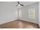Bright bedroom with hardwood floors, a ceiling fan, two windows, and crisp white walls at 112 Pointe Park Cir, Holly Springs, NC 27540
