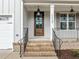 Inviting front porch features brick steps, metal railings and a wood front door at 112 Pointe Park Cir, Holly Springs, NC 27540